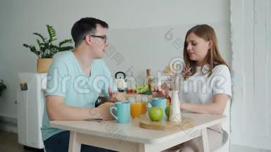 男人和女人一起吃羊角面包，一起坐在餐桌旁聊天